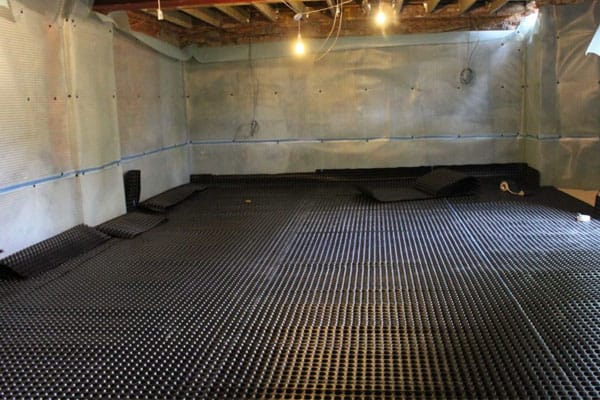 Dimpled drainage membrane installed on basement floor for waterproofing in Boston.