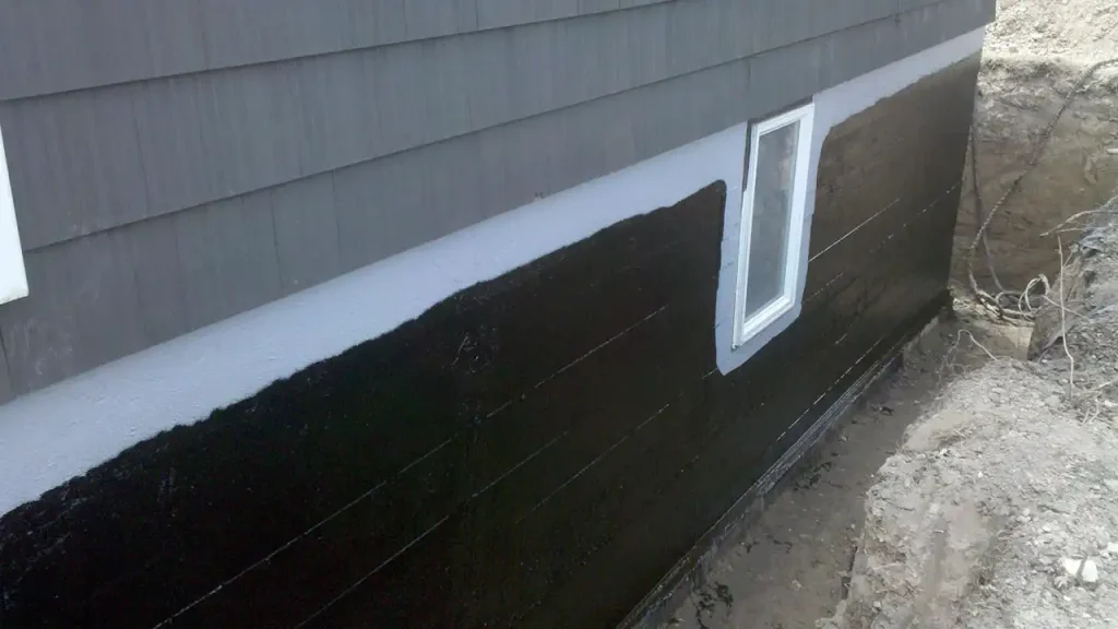 Black exterior foundation waterproofing membrane applied below siding in Boston.