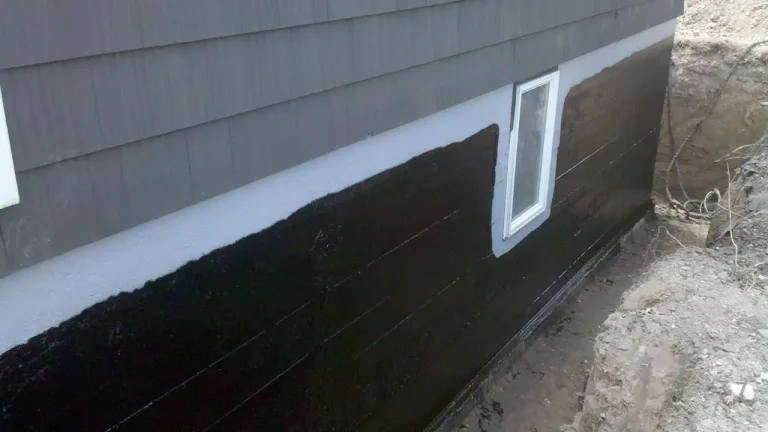 Black exterior foundation waterproofing membrane applied below siding in Boston.